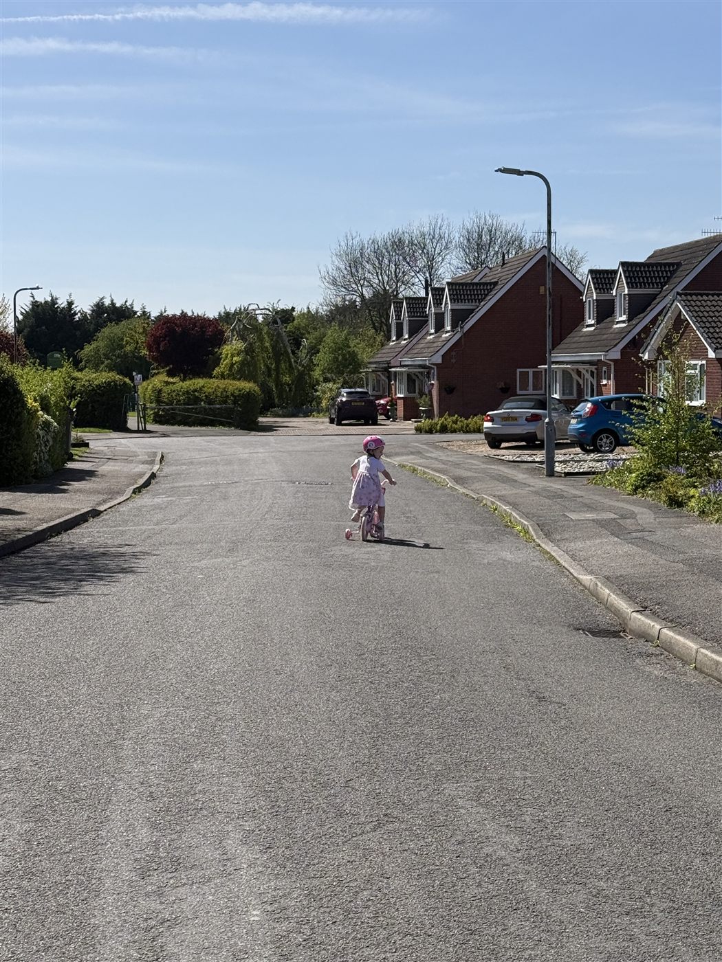 A child cycling down a sunny suburban street